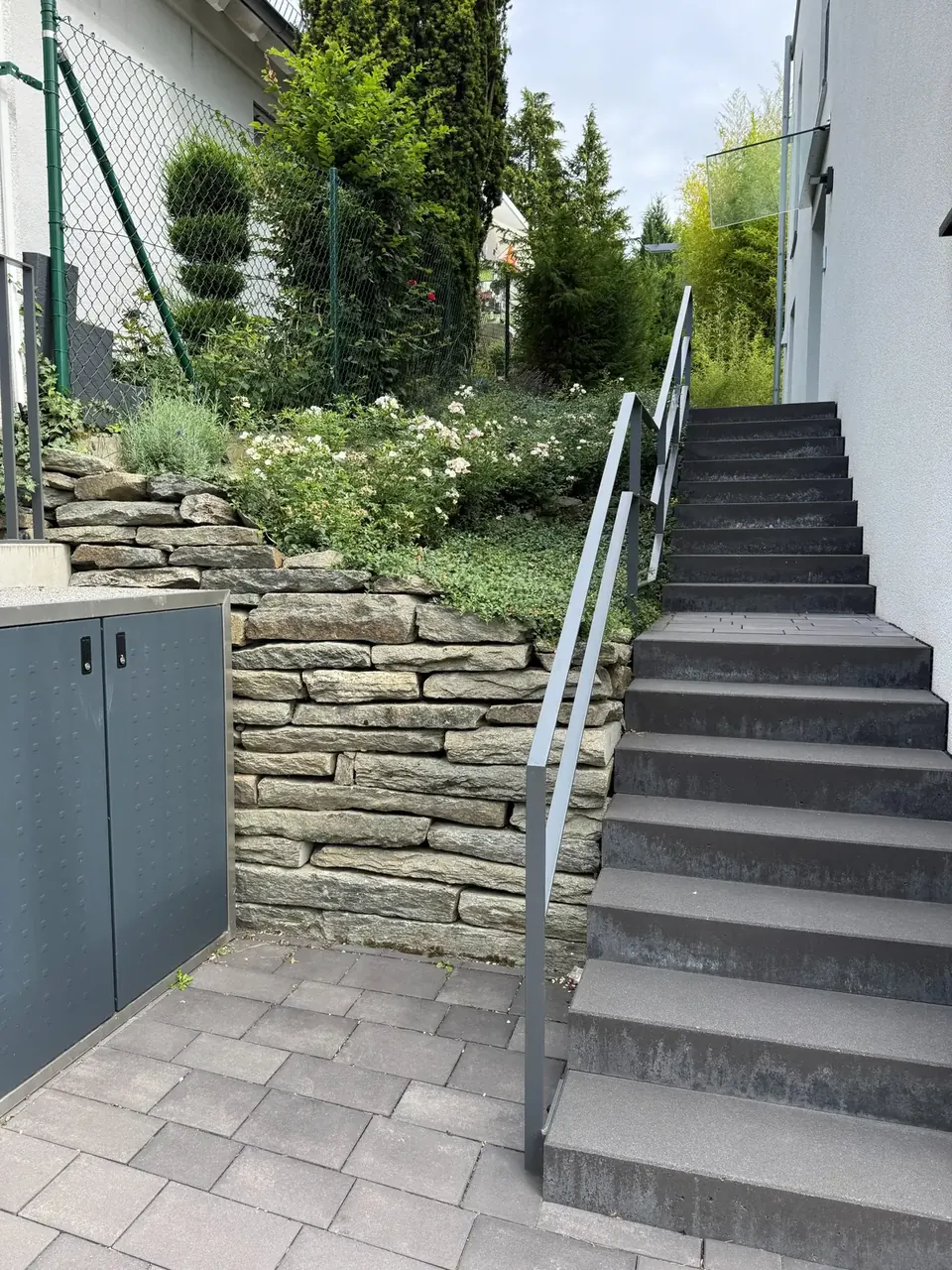 Natursteinmauer mit angrenzender Außentreppe als Übergang zwischen Geländehöhen